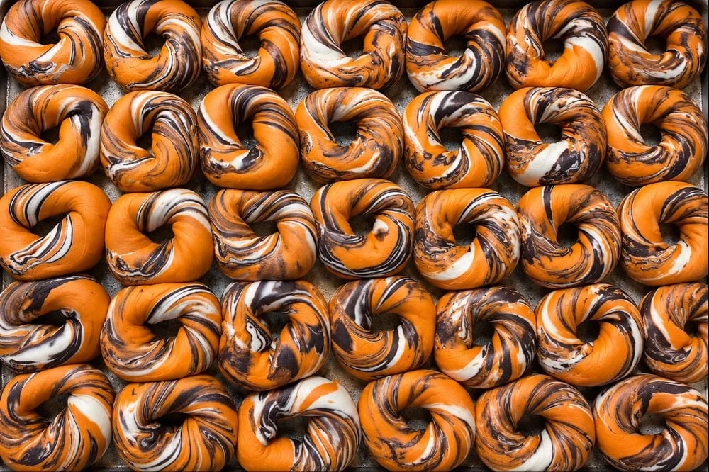 A tray of freshly baked marbled orange and black bagels